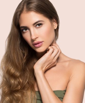 Woman beautiful face healthy. Beauty young model touching herself. Color background. Pink